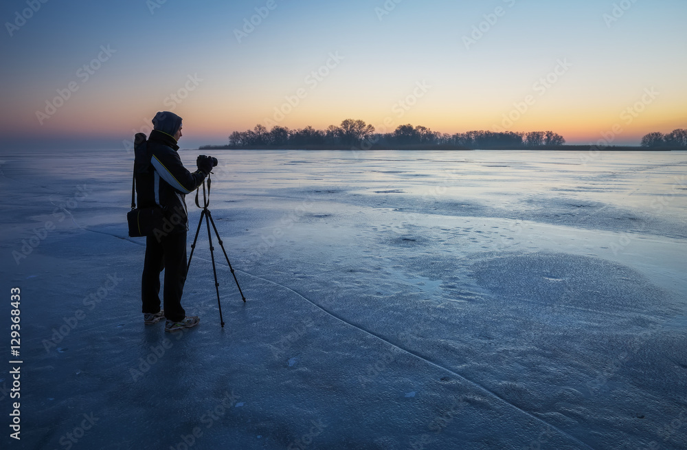 Photographer take pictures on the ice during sunset
