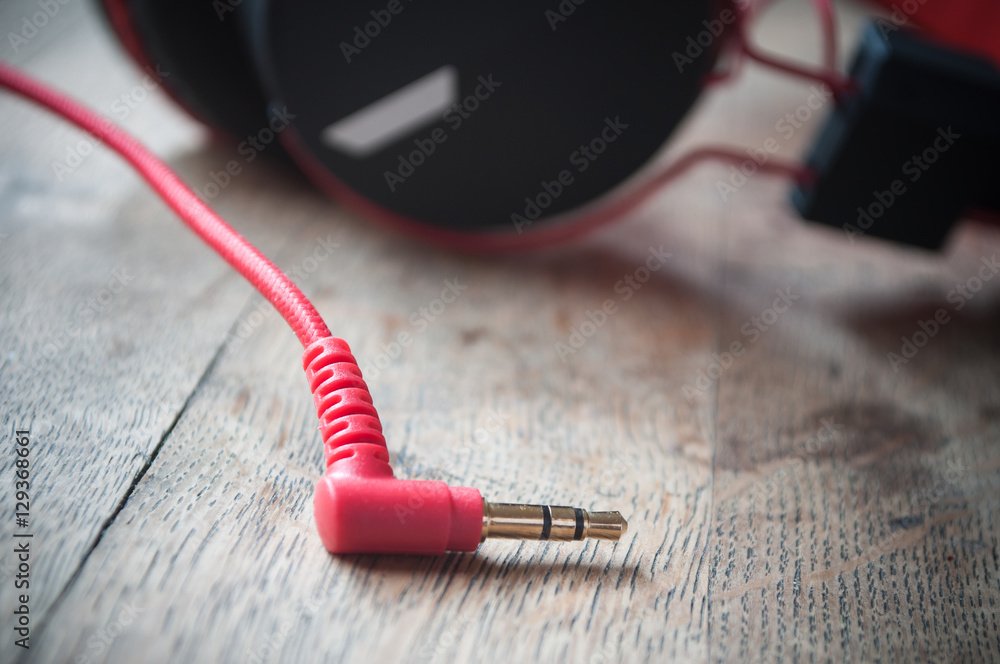 détail prise jack et casque audio rouge et noir sur table en vieux bois détail prise jack et casque audio rouge et noir sur table en vieux bois