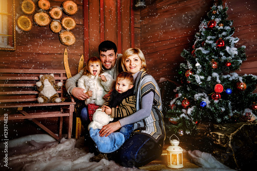Happy family sitting near a Christmas tree in the evening in anticipation of Christmas