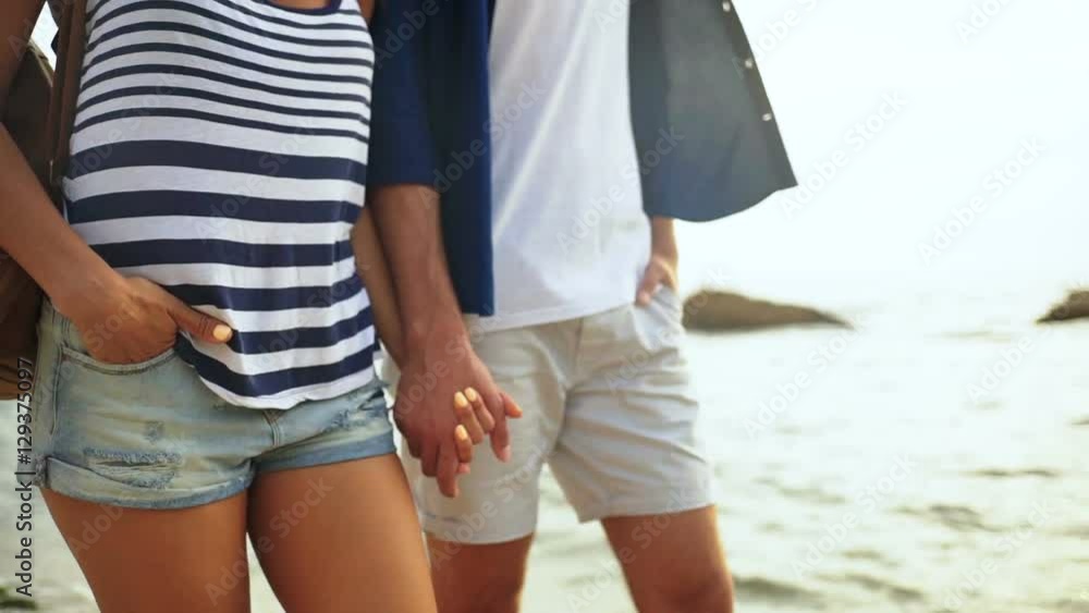 Close up of two young people holding hands and walking on the beautiful beach. Close up of two young people holding hands and walking on the beautiful beach.