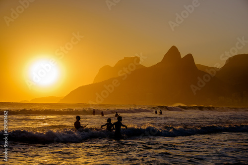 Unidentifiable silhouettes enjoying late afternoon sun rays on Ipanema beach in Rio de Janeiro, Brazil. Ipanema is one of the most expensive places to live in Rio.