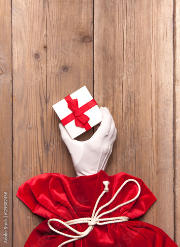 Santa Claus hand give a present from the red bag on Old Wooden Background photo