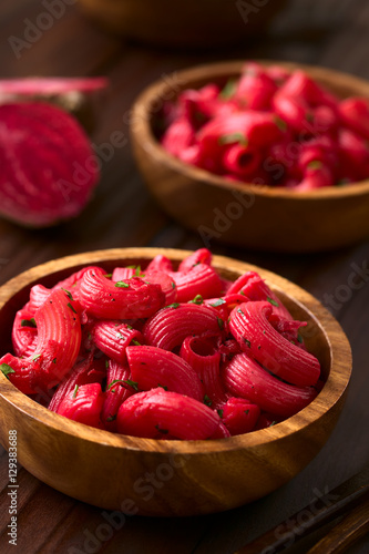 Macaroni pasta with beetroot and parsley in wooden bowls, photographed with natural light (Selective Focus, Focus in the middle of the first dish) photo