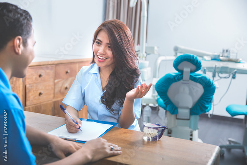 attractive dentist talking to her patient at clinic
