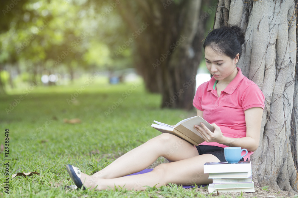 young asian woman reading book in the park