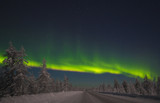 picture of massive multicoloured green vibrant Aurora Borealis, Aurora Polaris, also know as Northern Lights in the night sky over winter landscape with road