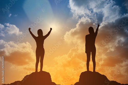 silhouette of winning success woman at sunset or sunrise standing and raising up her hand in celebration of having reached mountain top summit goal.business success concept.do it for success concept