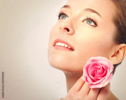 Young woman with blue eyes holding a pink rose