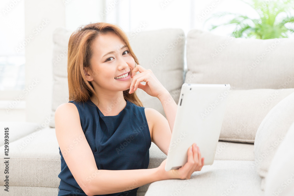 部屋でタブレットを見る女性 部屋でタブレットを見る女性