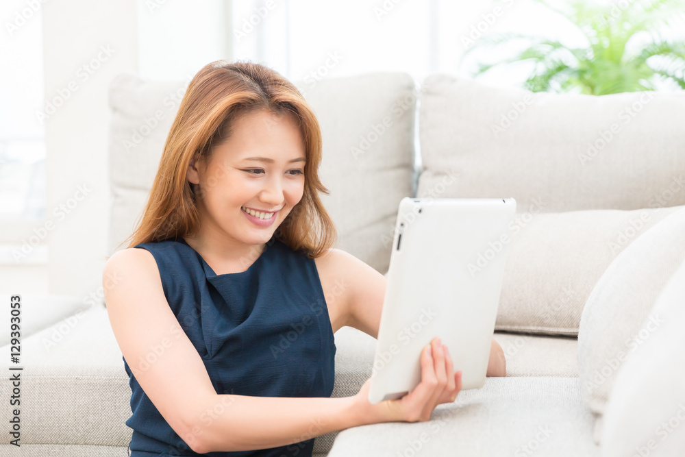 部屋でタブレットを見る女性 部屋でタブレットを見る女性