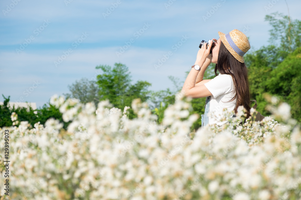 Asian hipster cute teen girl with camera in white flower garden,