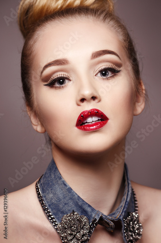 Beauty fashion portrait of a beautiful girl with bright makeup and red lipstick with rhinestones on her lips.