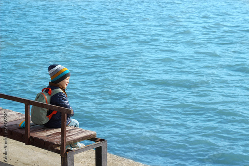 cute baby boy child with a cell phone on a bench outdoors on the