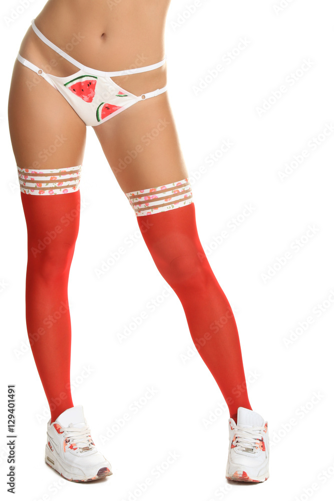 Sporting sexy legs in red stockings and white sneakers on a white background isolated. Sporting sexy legs in red stockings and white sneakers on a white background isolated.