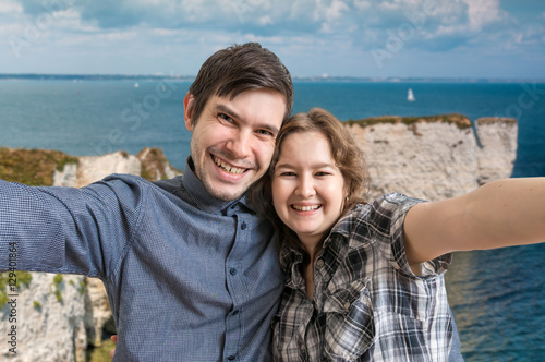 Young happy couple is taking selfie photo on vacation near sea.