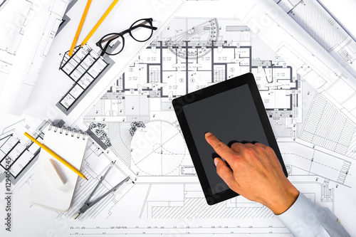 Construction plans and Male Hands using a Tablet on blueprints