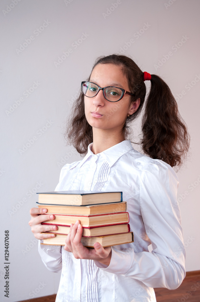 Schoolgirl with glasses holding a stack of books Schoolgirl with glasses holding a stack of books