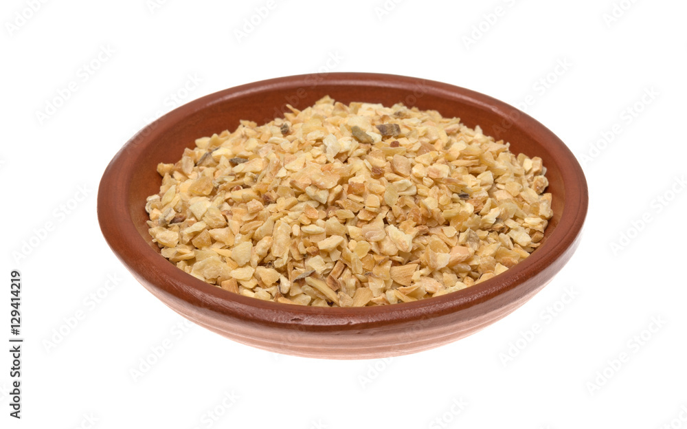 Dried minced garlic in a small bowl isolated on a white background. Dried minced garlic in a small bowl isolated on a white background.
