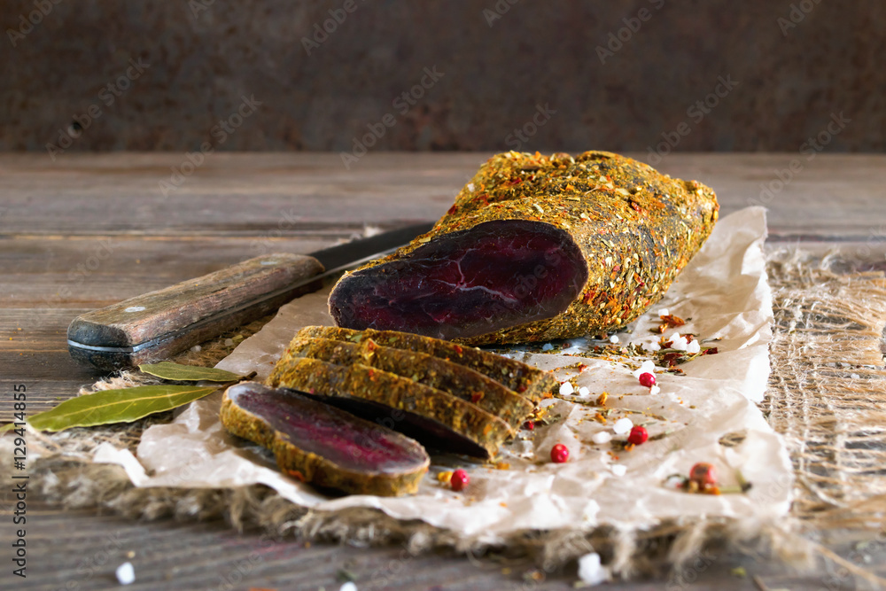 A piece of dried meat cut into slices lying on the kitchen table A piece of dried meat cut into slices lying on the kitchen table