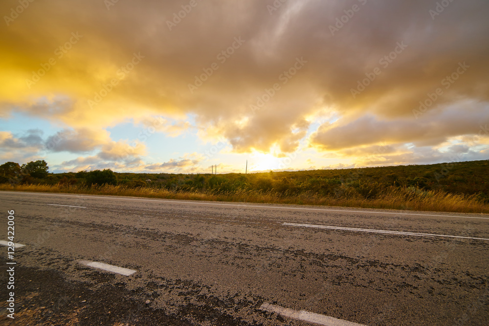 Picturesque landscape scene and sunset above road