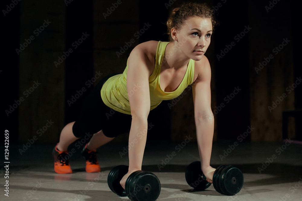 Woman doing push-ups on dumbbells in the gym. Woman doing push-ups on dumbbells in the gym.