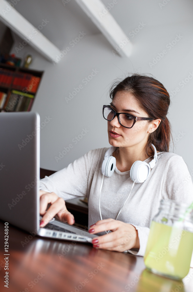 Young female student at home.She sitting in her living room and typing something on laptop.E-learning. Young female student at home.She sitting in her living room and typing something on laptop.E-learning.