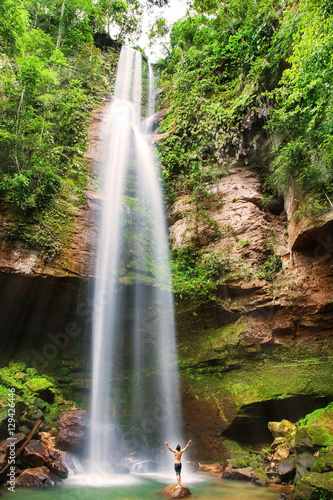 A man with arms open wide under a huge waterfall in Brazil
