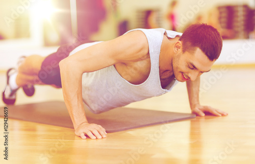 smiling man doing push-ups in the gym