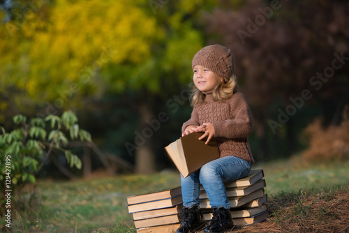 маленькая девочка читает книгу в парке