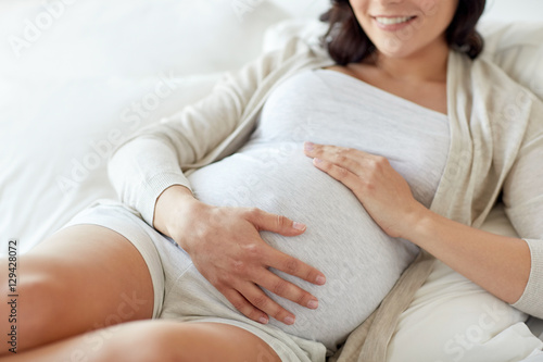 close up of happy pregnant woman in bed at home