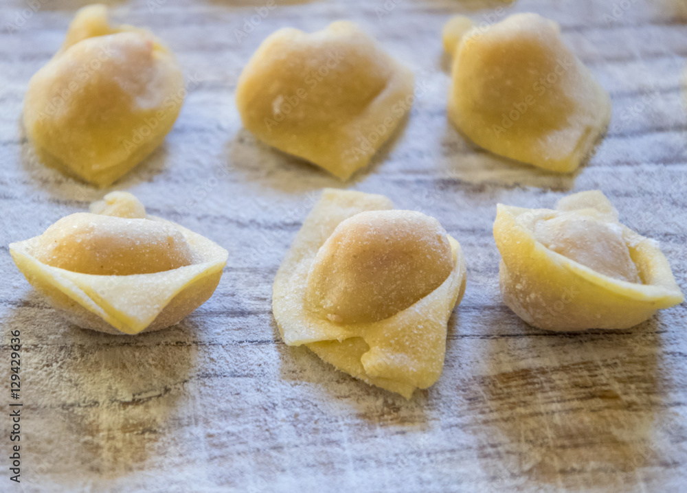 Raw italian cappelletti, fresh homemade pasta stuffed with cheese and meat on rustic wood table. Natural light. Raw italian cappelletti, fresh homemade pasta stuffed with cheese and meat on rustic wood table. Natural light.