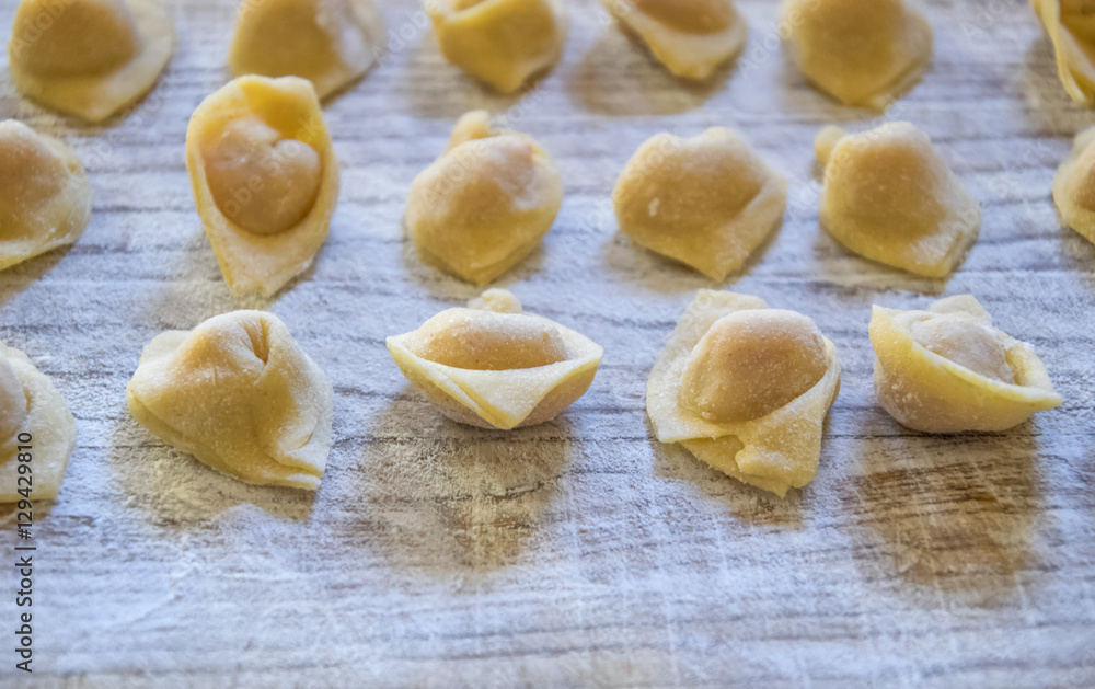 Raw italian cappelletti, fresh homemade pasta stuffed with cheese and meat on rustic wood table. Natural light. Raw italian cappelletti, fresh homemade pasta stuffed with cheese and meat on rustic wood table. Natural light.