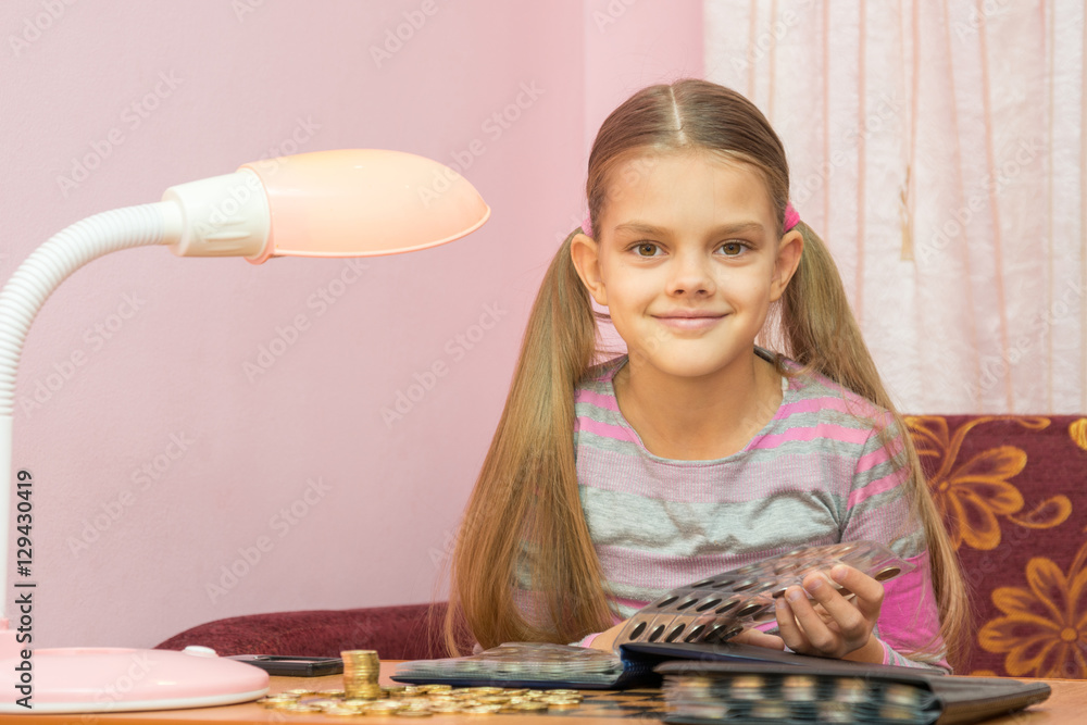 The child leafing through an album for collectors of coins and looked into the frame The child leafing through an album for collectors of coins and looked into the frame