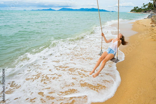 Young woman swinging on a beach swing. Selective focus. Hairs in motion blur.
