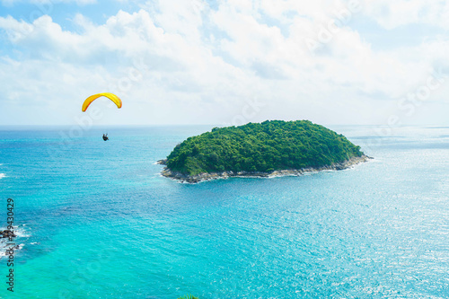 Skydiver flying over the water with island. Paragliding concept.