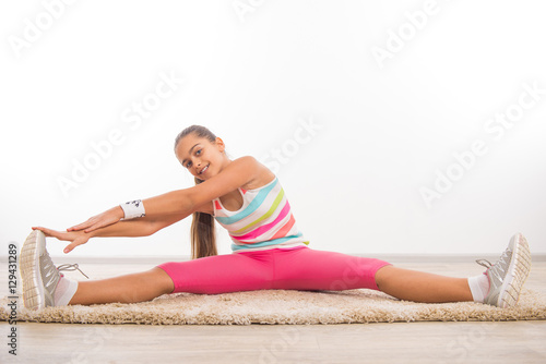 Beautiful teenage girl doing stretching exercises, girl on the carpet at home exercise. Beautiful teen girl Physical exercise doing in home environment, physical exercise for schoolchildren 