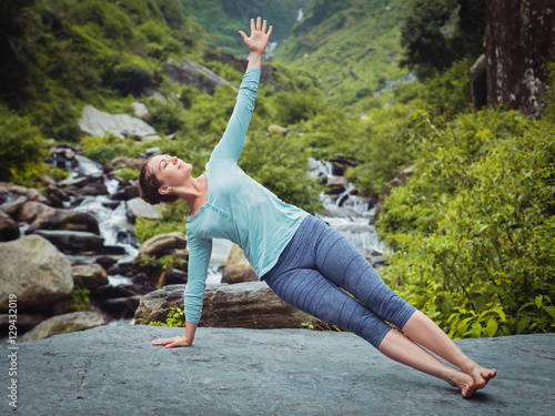 Woman doing yoga asana Vasisthasana - side plank pose outdoors photo