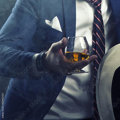 Man wearing suit holding cognac glass