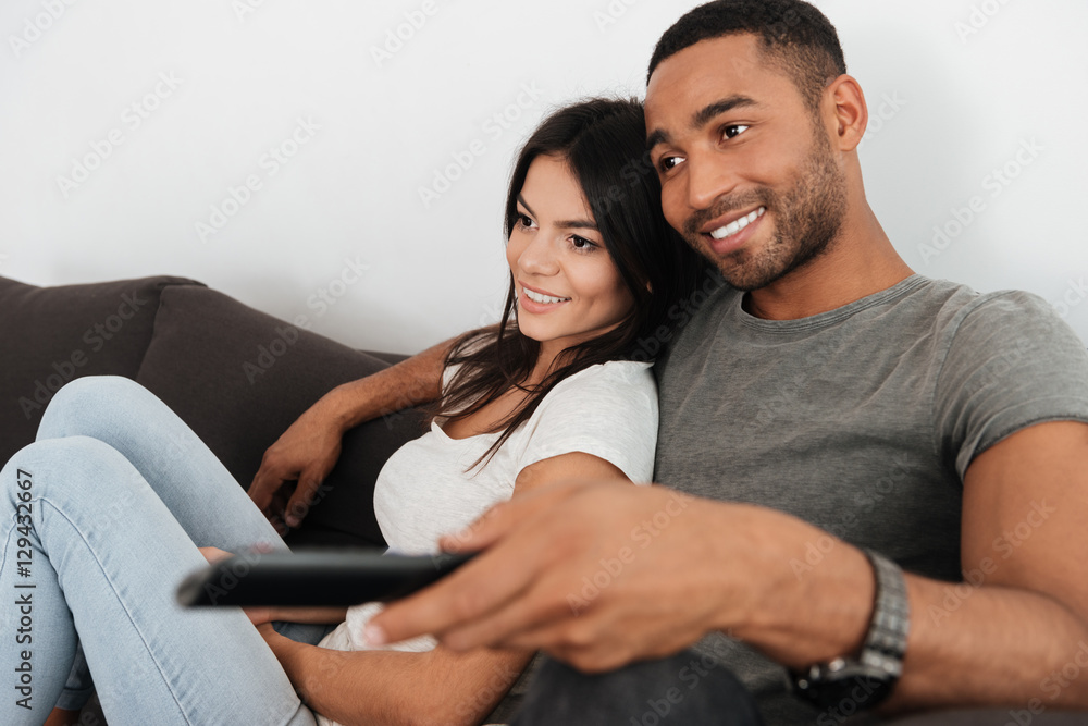 Young couple hugging and watching TV on sofa at home Young couple hugging and watching TV on sofa at home
