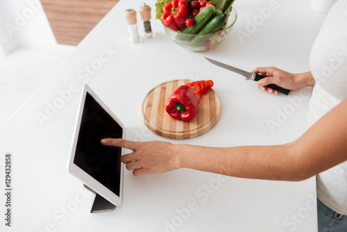 Cropped image of woman reading recipe from tablet computer