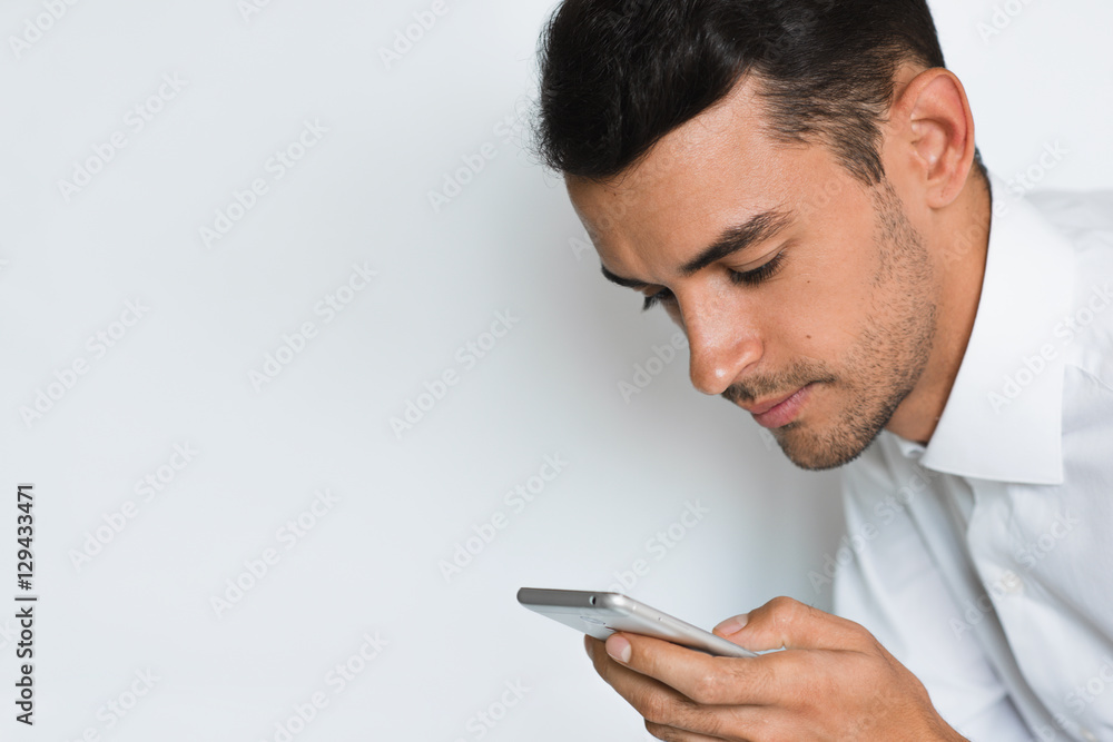 Portrait of handsome man send texting on mobile phone isolated against gray background. Technology and connection idea. Young caucasian businessman posing in studio with smart phone. Portrait of handsome man send texting on mobile phone isolated against gray background. Technology and connection idea. Young caucasian businessman posing in studio with smart phone.