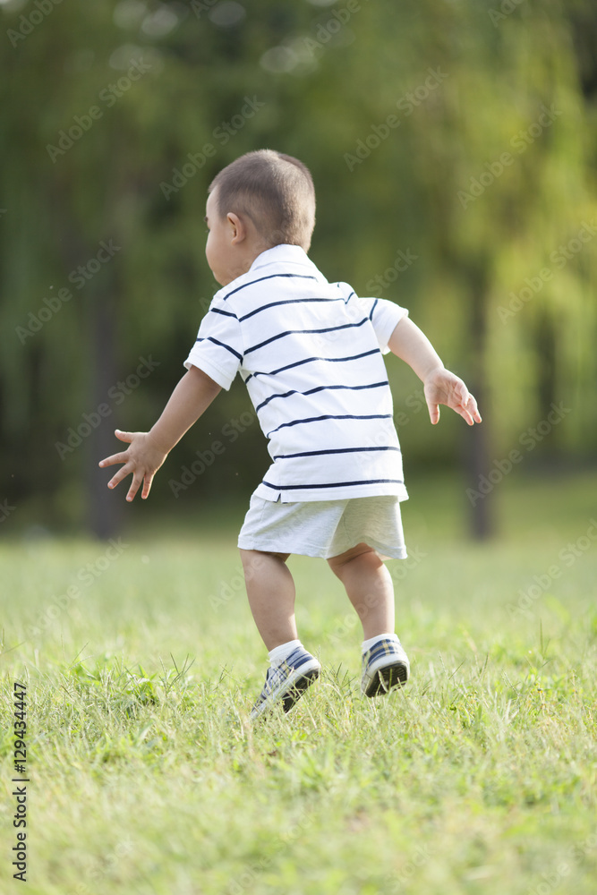 Happy Chinese baby boy jumping in meadow