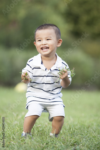 Happy Chinese baby boy holding grass in hands