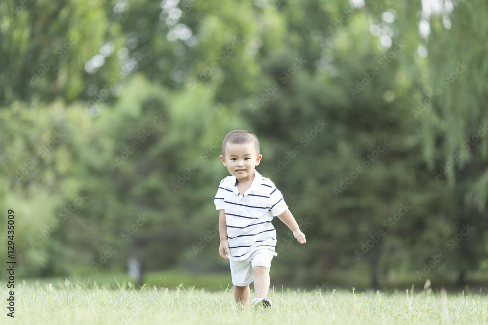 Happy Chinese baby boy running in meadow Happy Chinese baby boy running in meadow