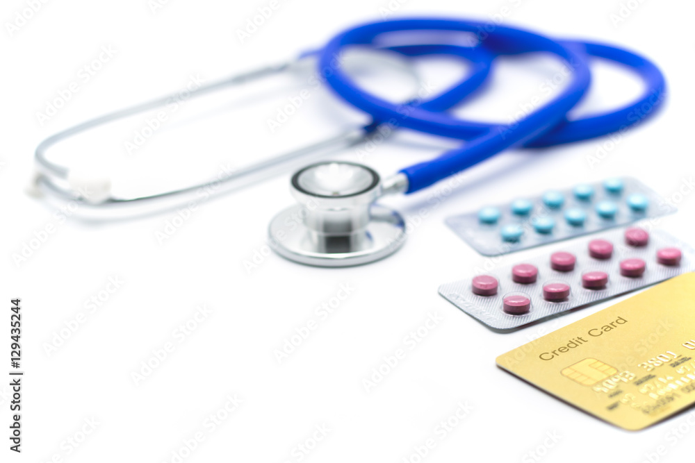 Credit card with medical stethoscope and pills on white backgrou Credit card with medical stethoscope and pills on white backgrou