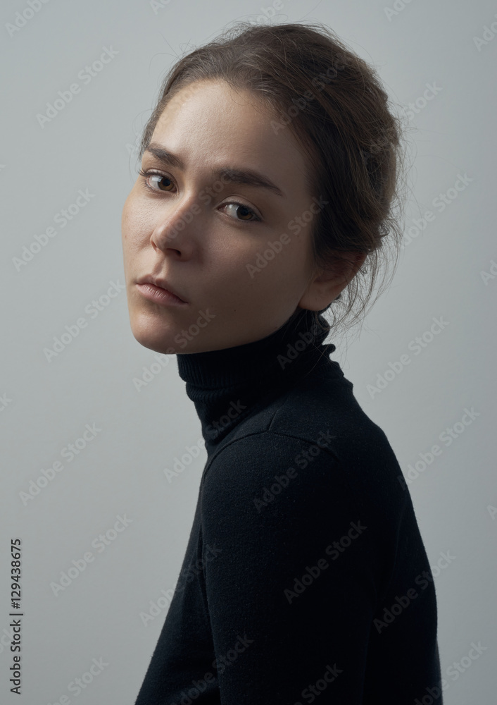 Dramatic portrait of a young beautiful girl with freckles in a black turtleneck on white background in studio Dramatic portrait of a young beautiful girl with freckles in a black turtleneck on white background in studio