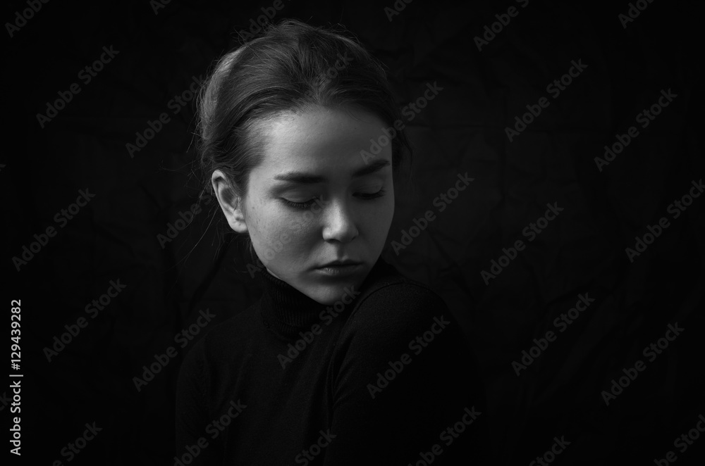 Dramatic black and white portrait of young beautiful girl with freckles in a black turtleneck on black background in studio Dramatic black and white portrait of young beautiful girl with freckles in a black turtleneck on black background in studio