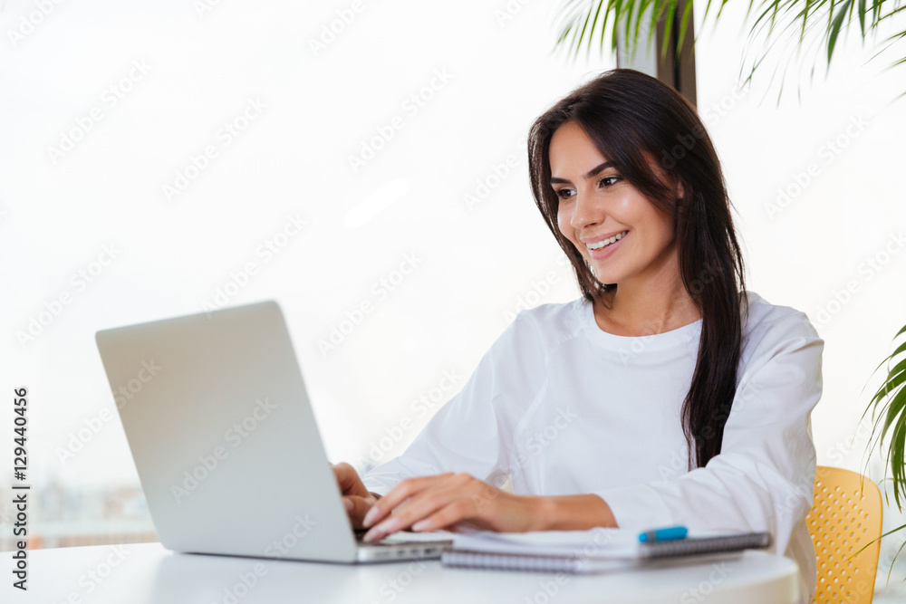 Happy businesswoman smiling and using laptop in office Happy businesswoman smiling and using laptop in office