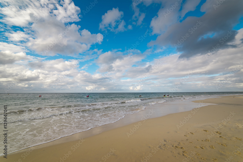 The Indian Ocean laps gently onto the white sandy shore of beautiful beach near Busselton, South Western Australia protected by Geographe Bay on a  blue sky and white cloud afternoon in early summer.