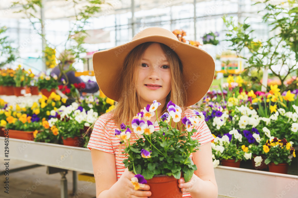 Adorable little girl choosing flowers in garden center